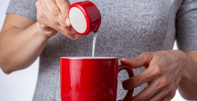 Coffee creamer being poured into a cup of coffee